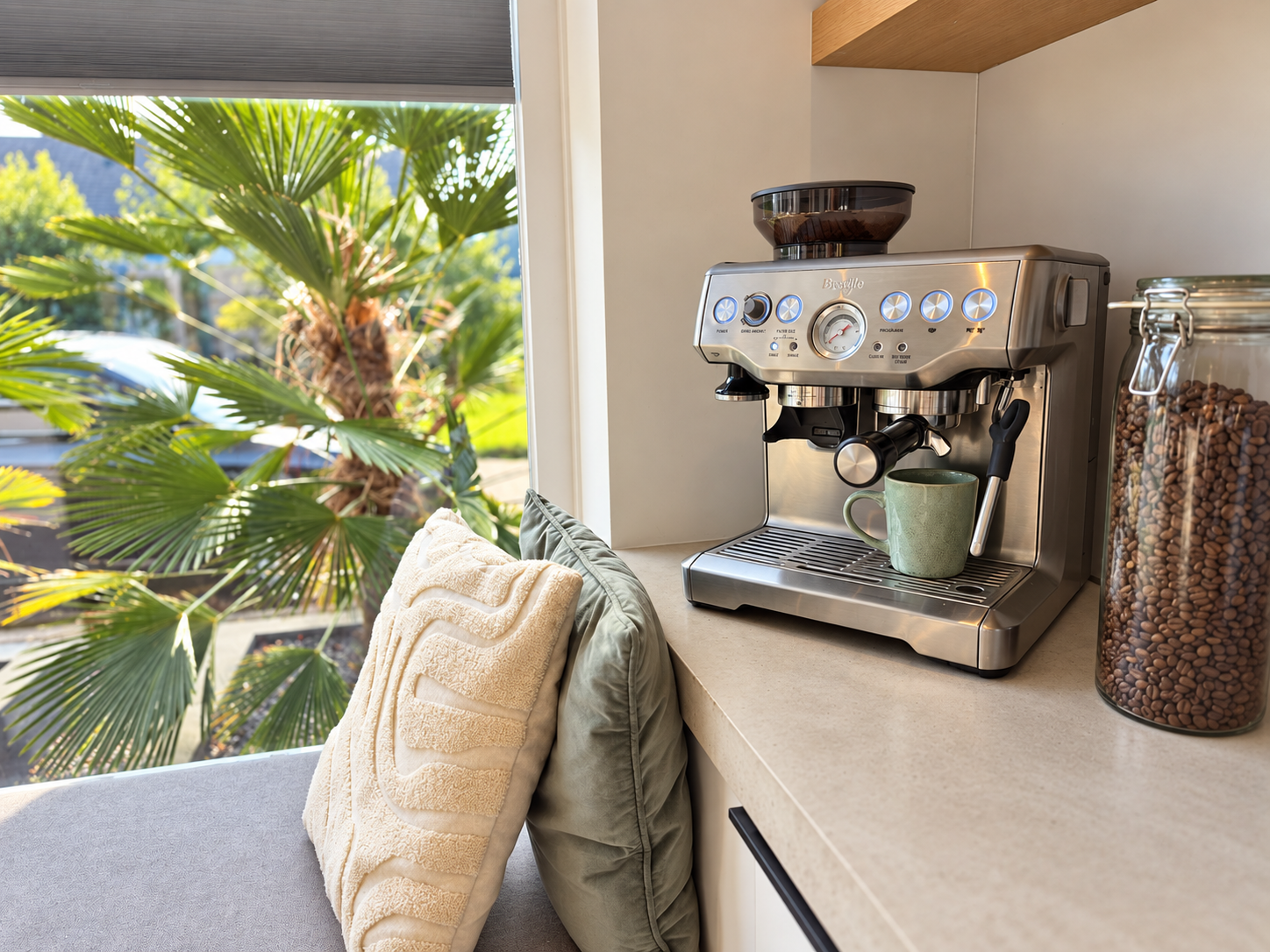 Koffiecorner met espressomachine bij een raam met palmen